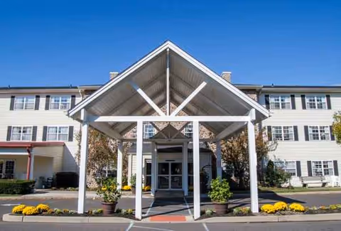 Exterior view of a senior living facility with a covered entrance and landscaping.