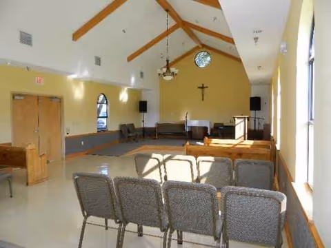 Interior chapel with pews, podium, cross, and stage at Kinder Retirement and Rehabilitation Center.