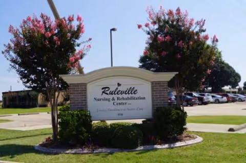 Exterior view of Ruleville Nursing and Rehabilitation Center sign with parked cars and trees