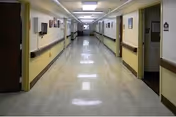 Long polished indoor hallway with doors and handrails on both sides in a care facility.