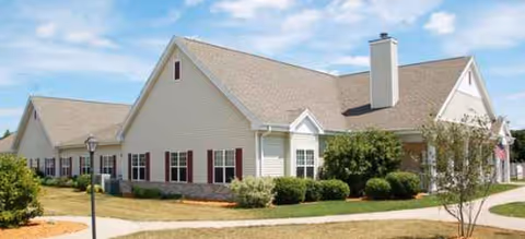 One-story beige Brookdale LaCrosse senior living building with shrubs and a walkway.