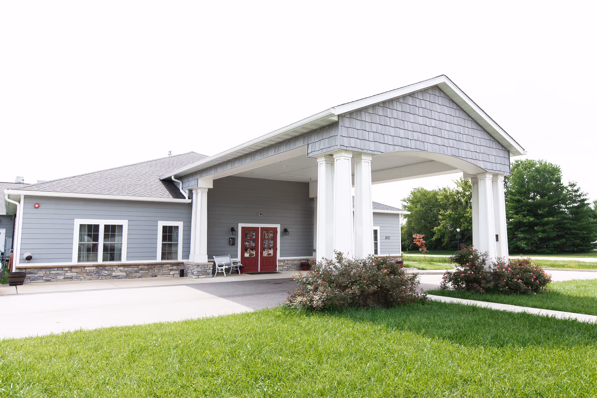Exterior view of Joe's Place entrance with red doors, white columns, and manicured landscaping.