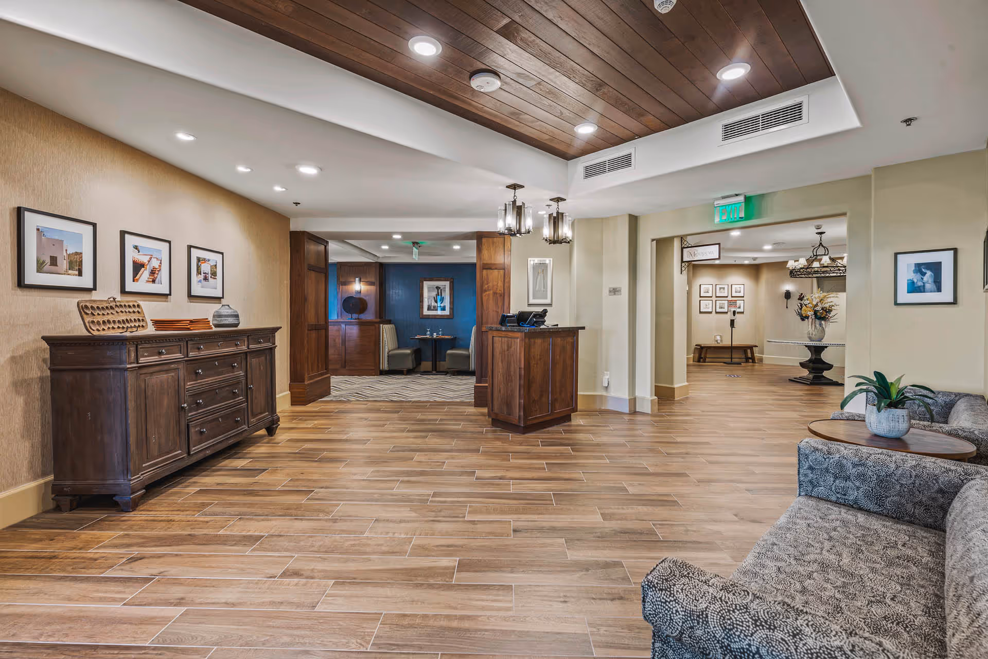 Spacious, wood-floored interior lobby with a reception desk, seating area, framed artwork, and decorative lighting.