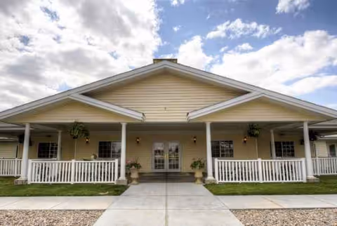 Single story beige senior living building with a wide front porch and columns.