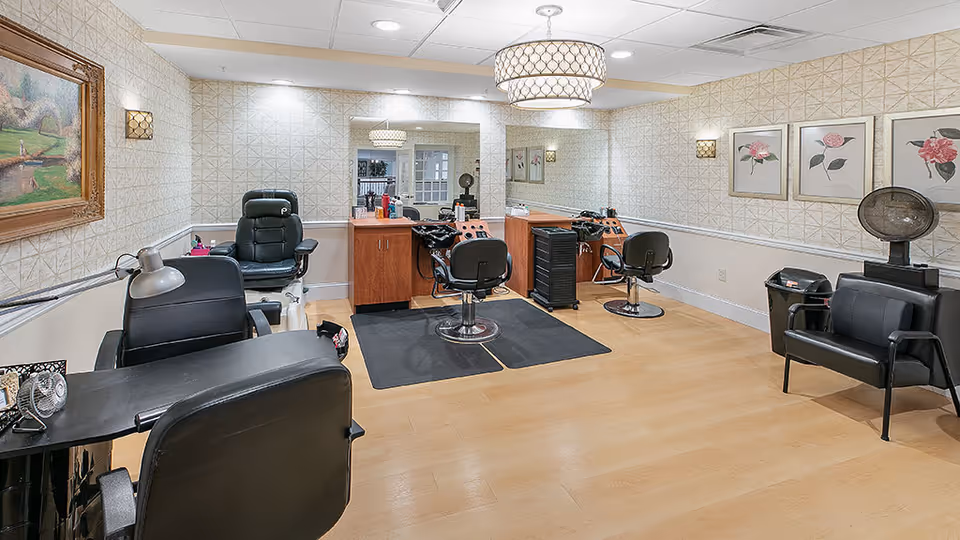 Well-lit salon room with styling chairs, mirrors, and hairdressing stations in a senior living facility.