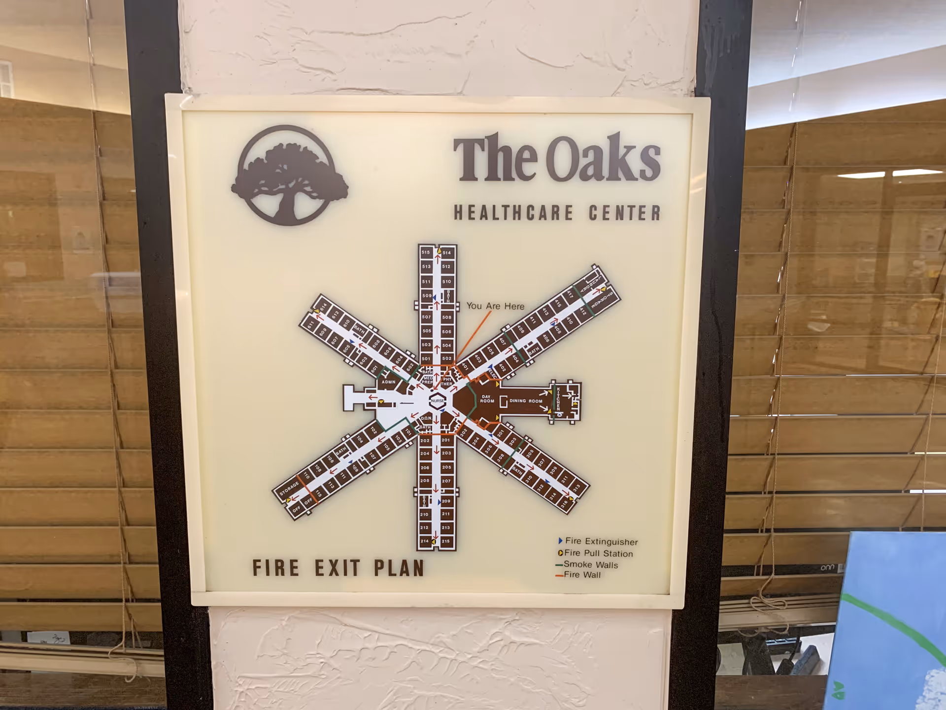Fire exit plan map of The Oaks Healthcare Center showing a star-shaped layout with labeled rooms and key locations such as fire extinguishers, fire pull stations, smoke walls, and fire walls.