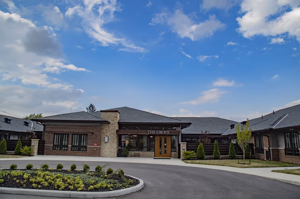 Brick building with glass entrance doors labeled The Grove, circular driveway, and landscaped front yard.