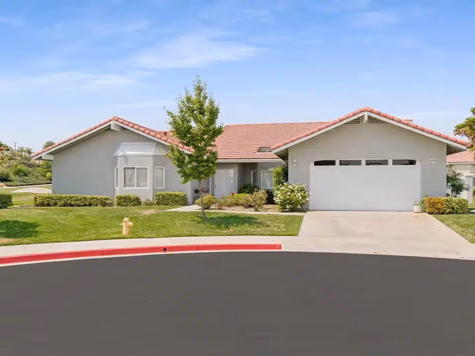 Single-story suburban home with a red tile roof, attached two-car garage, front lawn, and driveway.