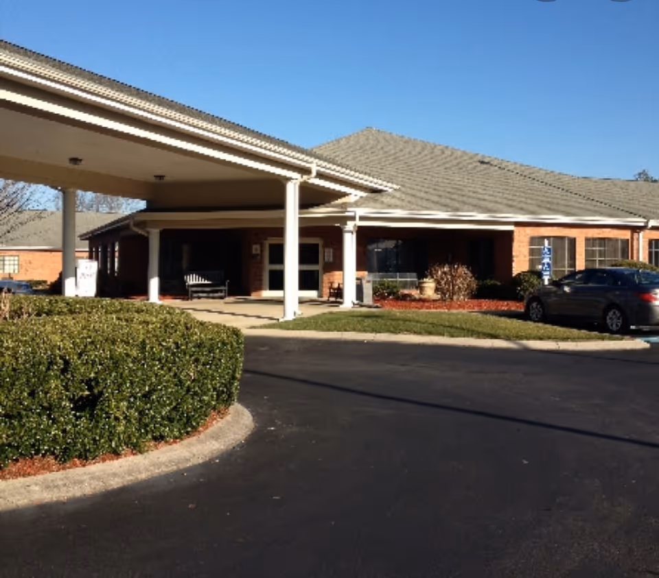 Exterior view of Soddy-Daisy Healthcare Center showing a single-story brick building with a covered entrance, a driveway, some bushes, and a parked car under a clear blue sky.