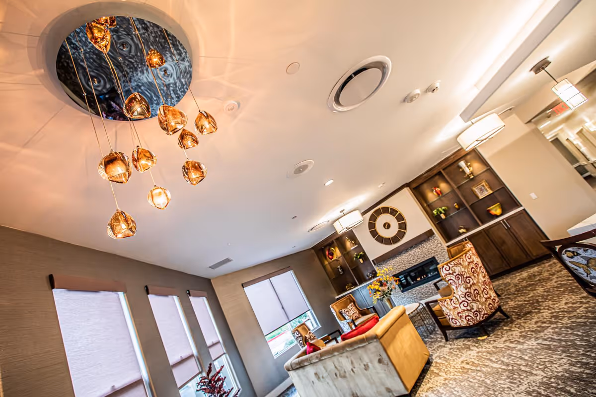 Communal lounge area with pendant lights, sofas and armchairs around a fireplace and built-in shelving.
