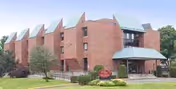 Red brick assisted living building with a covered entrance and angular rooflines