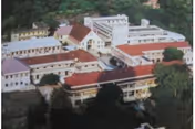 Aerial view of a multi-building facility with red roofs and light-colored walls surrounded by trees.
