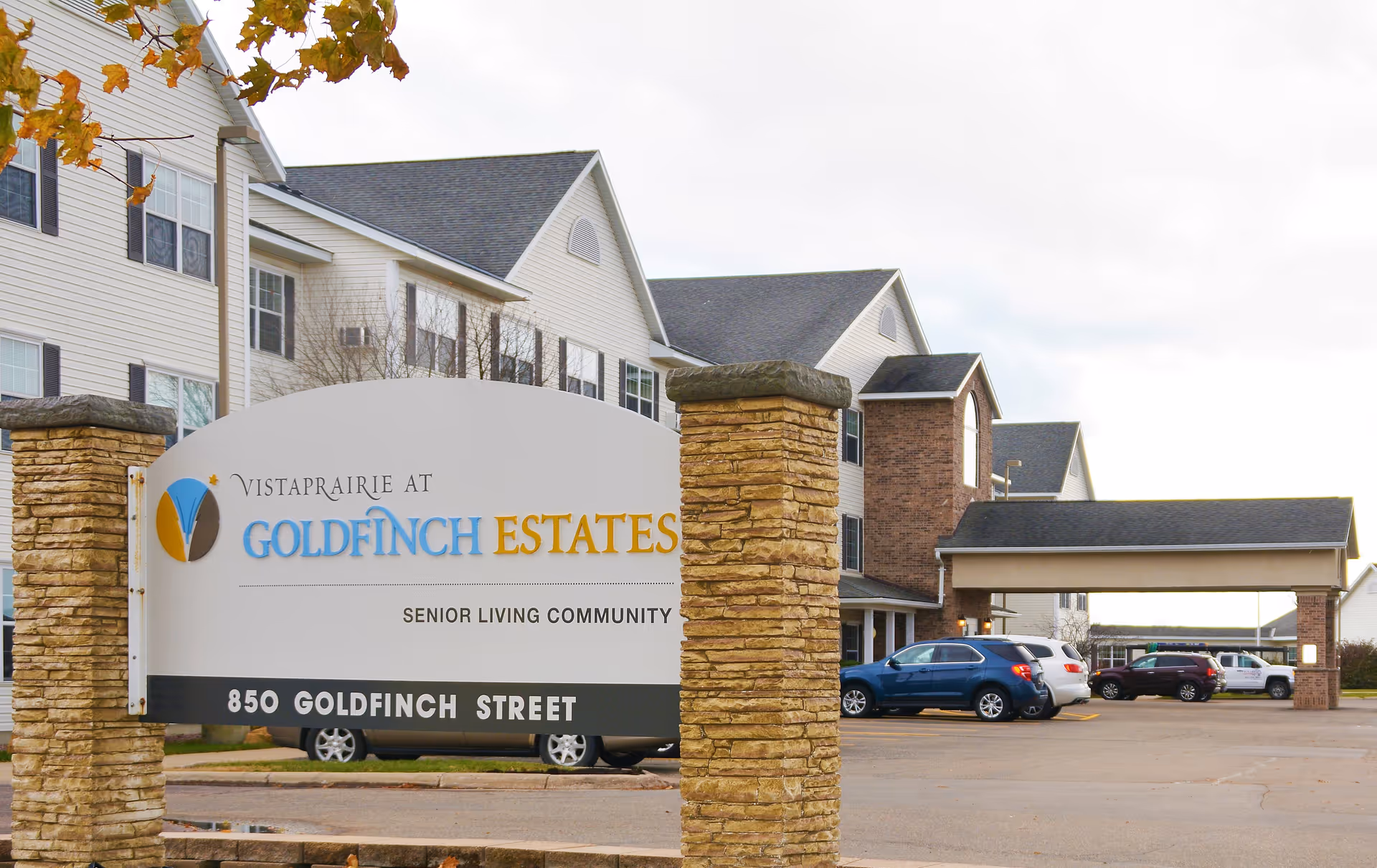Entrance sign for Vista Prairie at Goldfinch Estates senior living community in front of the multi-story building and parking area.