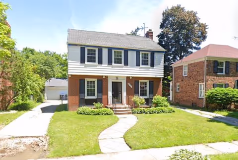 Two-story house with white siding, brick base, and curved front walkway.