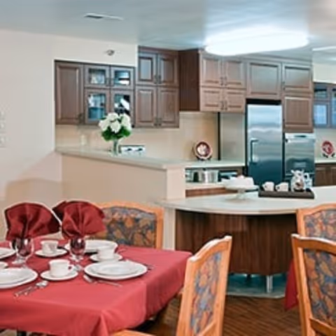 Dining area with red tablecloths, place settings, and curved kitchen island in the background.