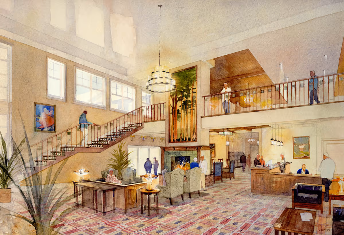A spacious, well-lit senior living facility common area with a high ceiling, large windows, and a staircase leading to an upper balcony. The room features comfortable seating around a fireplace, several people interacting, and a reception desk on the right side. The decor includes plants, paintings, and a large vertical artwork above the fireplace.