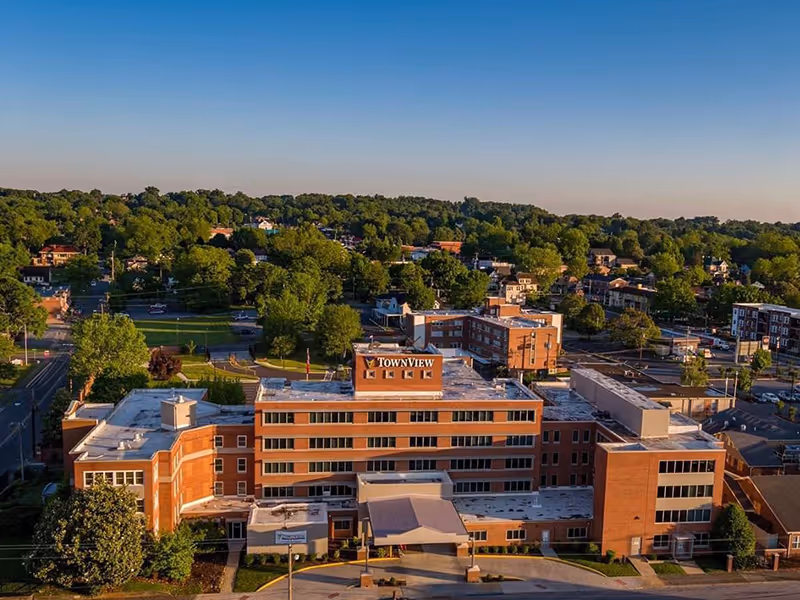 Aerial view of the multi-story brick TownView senior living building with surrounding neighborhood and trees.