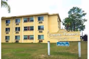Three-story yellow building labeled Campus Towers with a front lawn sign.