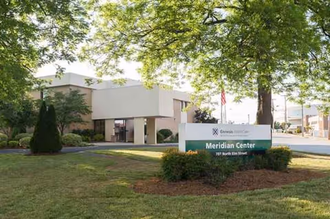 Exterior view of Meridian Center with sign, trees, and a manicured lawn