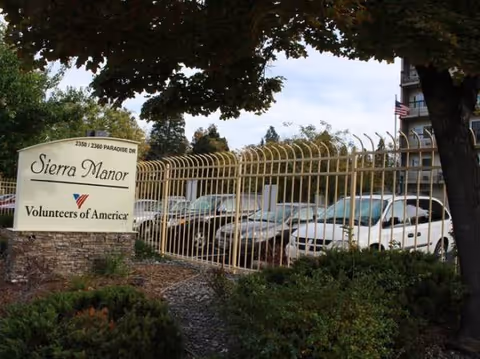 Front entrance of Sierra Manor with a gated driveway and sign.