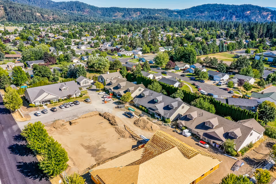 Aerial view of a senior living facility named Dalton Senior Living under construction, surrounded by residential houses and greenery with a mountainous backdrop.