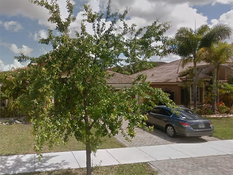 Single-story senior living facility exterior with a parked car and lush landscaping.