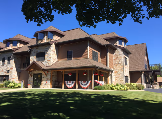 Exterior view of a large assisted living facility with stone and wood facade and bunting