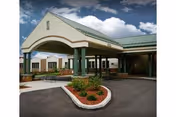 Exterior view of Avalon Springs Care Center entrance with green columns and landscaping.