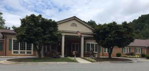 The Elms of Lynchburg exterior with brick facade, entrance, and surrounding trees.