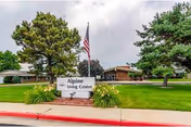 Front exterior of a single-story senior living facility with a sign reading "Alpine Living Center", a flagpole, and landscaped lawn.