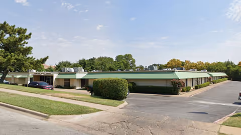 Exterior view of a single-story River Oaks facility with green trim, parking, and landscaping.