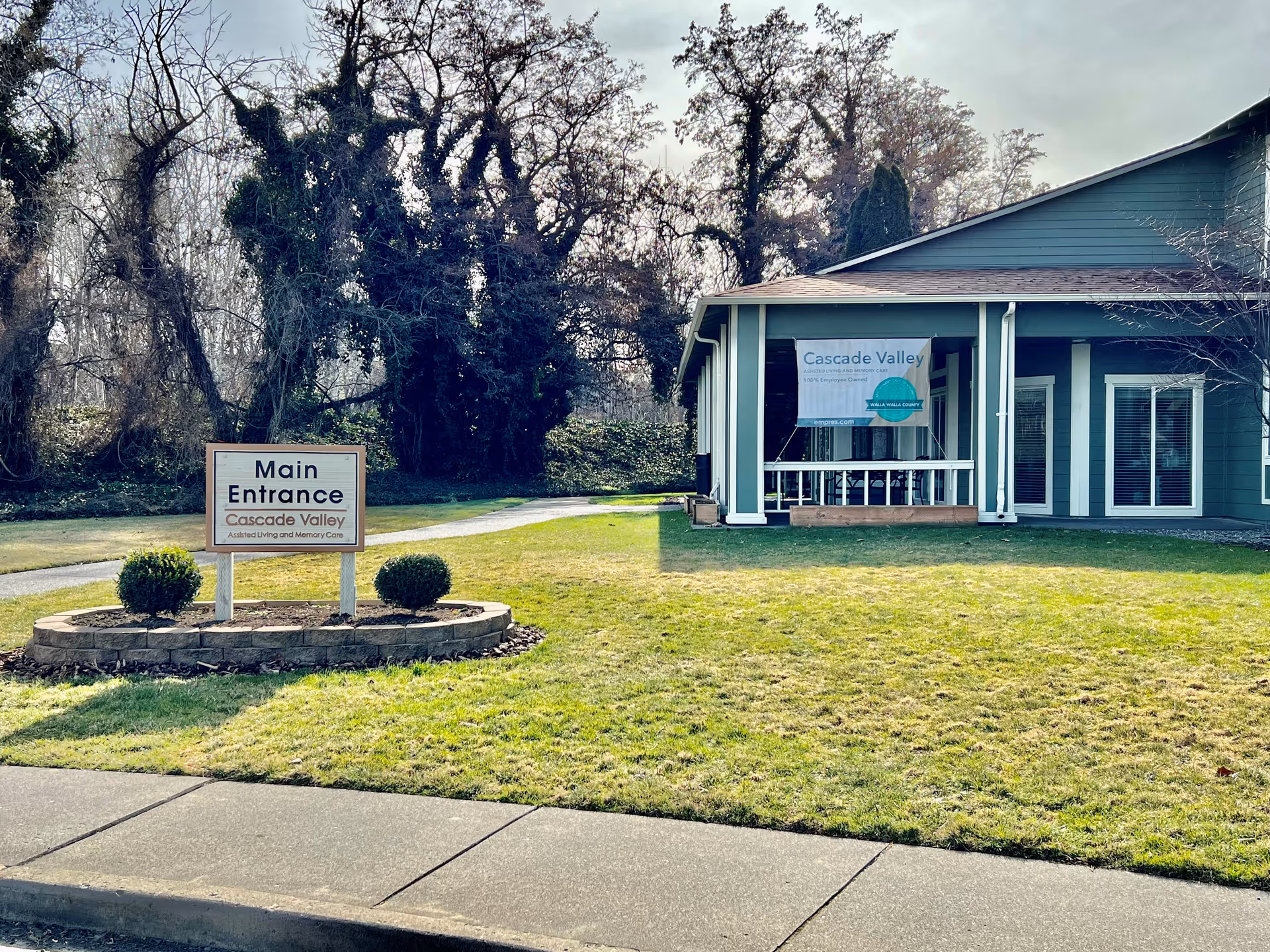 Front exterior of Cascade Valley Assisted Living and Memory Care with a 'Main Entrance' sign on the lawn.