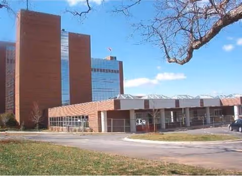 Exterior view of a hospital with brick towers and a modern glass-front entrance.
