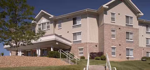 Two-story senior living facility with beige brick exterior and a covered entrance.