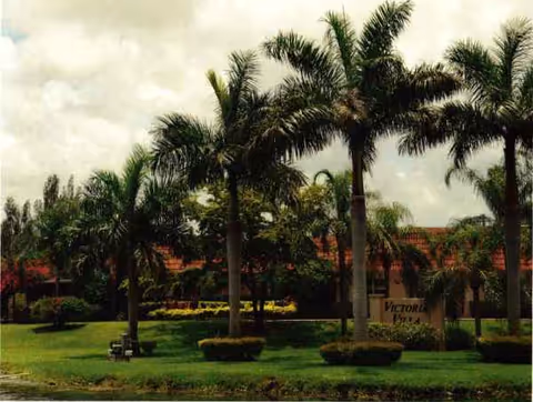 Exterior view of Victoria Villa with palm trees, manicured lawn, and building facade.