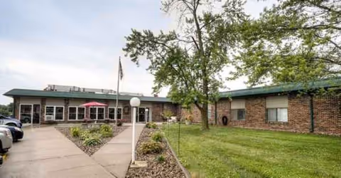 Exterior view of Cameron Nursing Center with brick building, walkway, parking lot, and green lawn.