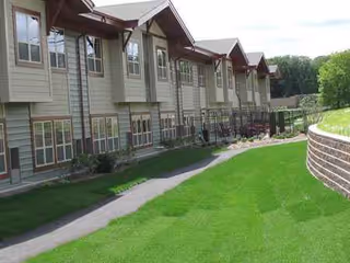 Exterior view of Trails of Orono Assisted Living and Memory Care building with lawn and walkway.