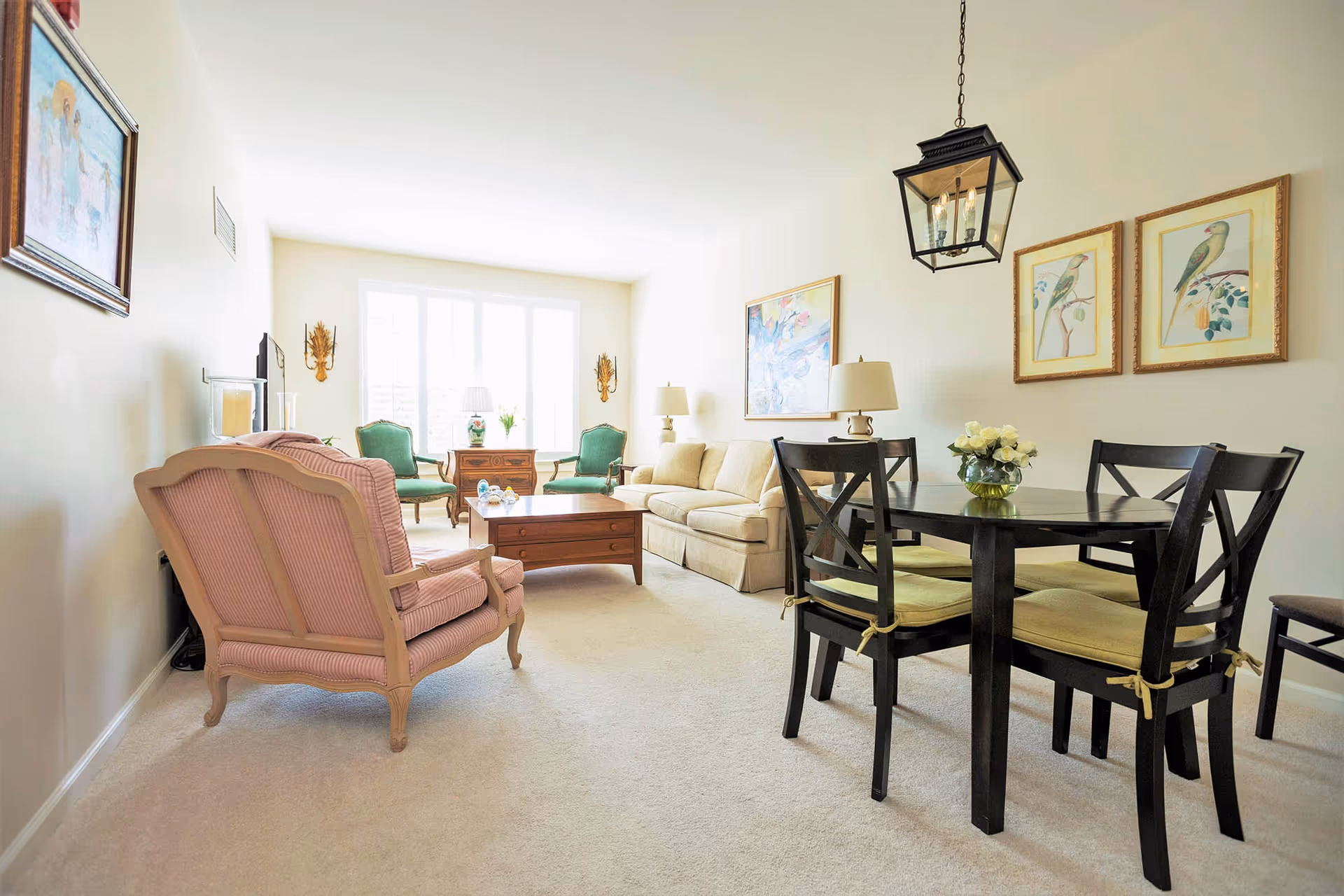 Bright combined living and dining room with sofa, armchairs, coffee table, and a round dining table with four chairs.