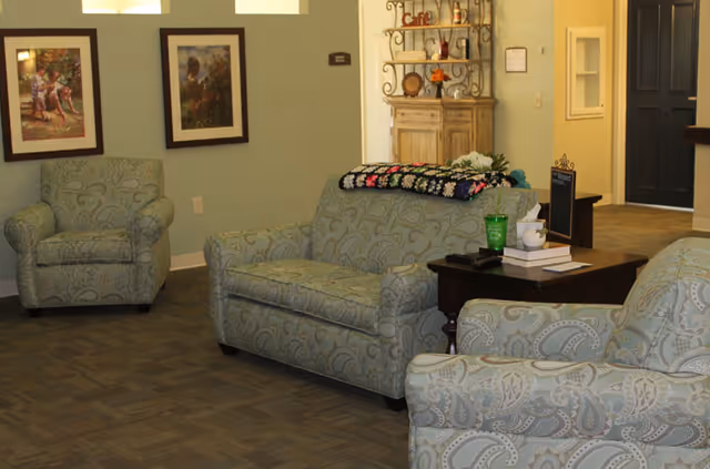 Light teal patterned sofas, chairs, and a dark coffee table in a cozy lobby seating area.