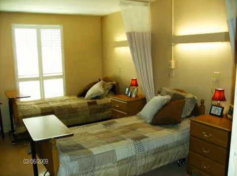 A shared resident bedroom with two single beds, nightstands, lamps, and curtains.