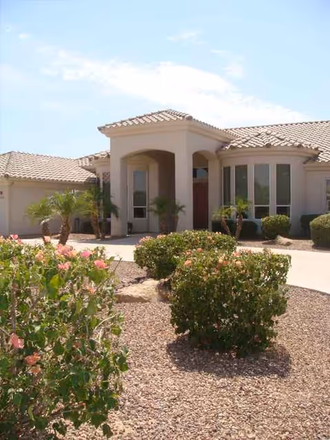 Front view of a single-story assisted living facility with desert landscaping and arches.