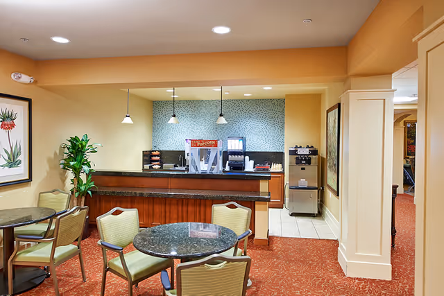 Small dining/lounge area with round tables and chairs and a counter serving snacks and beverages including a popcorn machine.