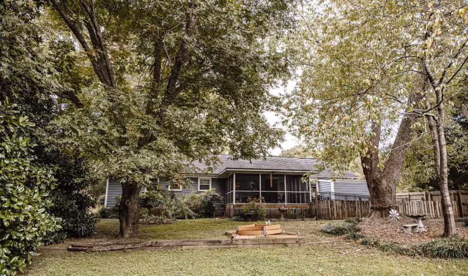 Vintage Gardens exterior shows a single-story building with front yard, trees, and screened porch.