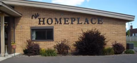 Brick facility exterior with The Homeplace sign and front shrubs.
