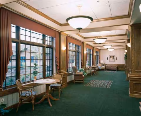 Long interior lounge area with green carpet, windows, and seating.