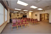 Rows of pink cushioned chairs facing a small stage in a bright community room.