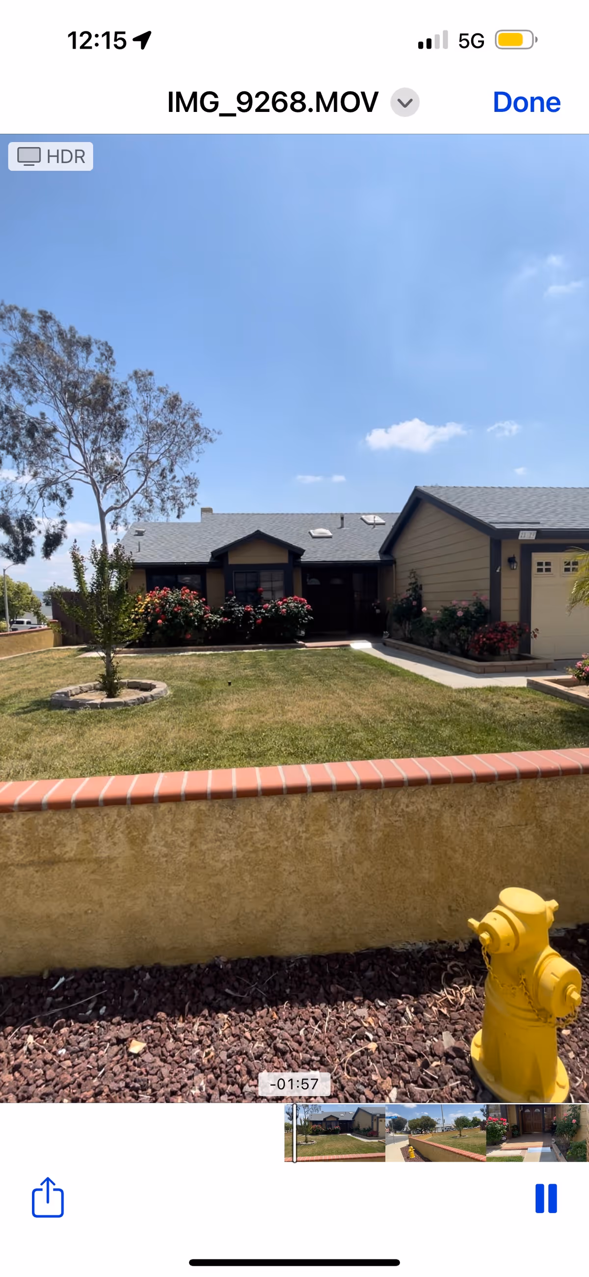 Front exterior of a single-story house with a lawn, flower beds, a low brick wall and a yellow fire hydrant in the foreground.