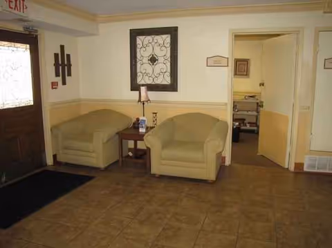 Two beige armchairs with a side table sit in a small lobby area.
