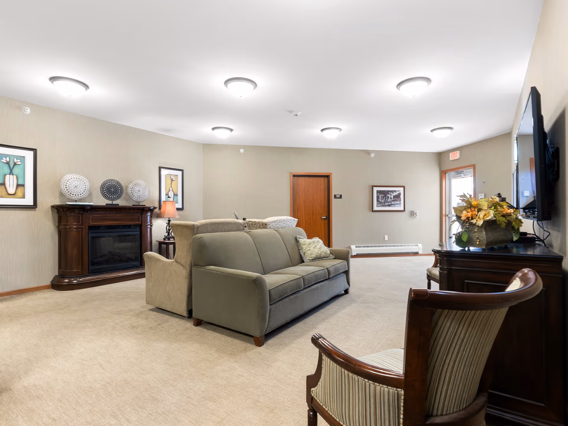 Spacious furnished lounge with sofas, chairs, a fireplace, wall-mounted TV and decorative accents.