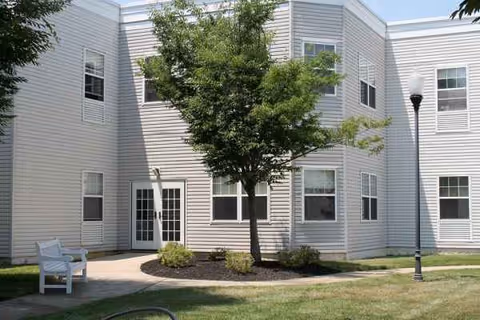 Exterior view of Mattison Crossing building with tree, bench, and street lamp near entrance.